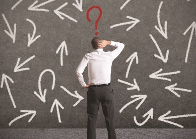 Man with question mark over head looking at wall with arrows going in different directions