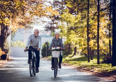 Older couple riding bikes in park