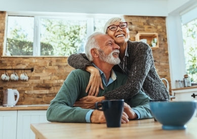Senior Couple Smiling and Hugging at Kitchen Table